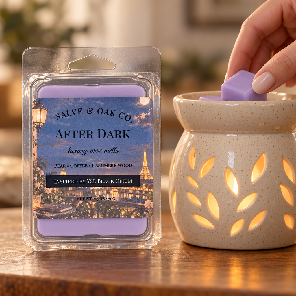 Hand placing a lavender After Dark wax cube into a glowing ceramic warmer beside its package.