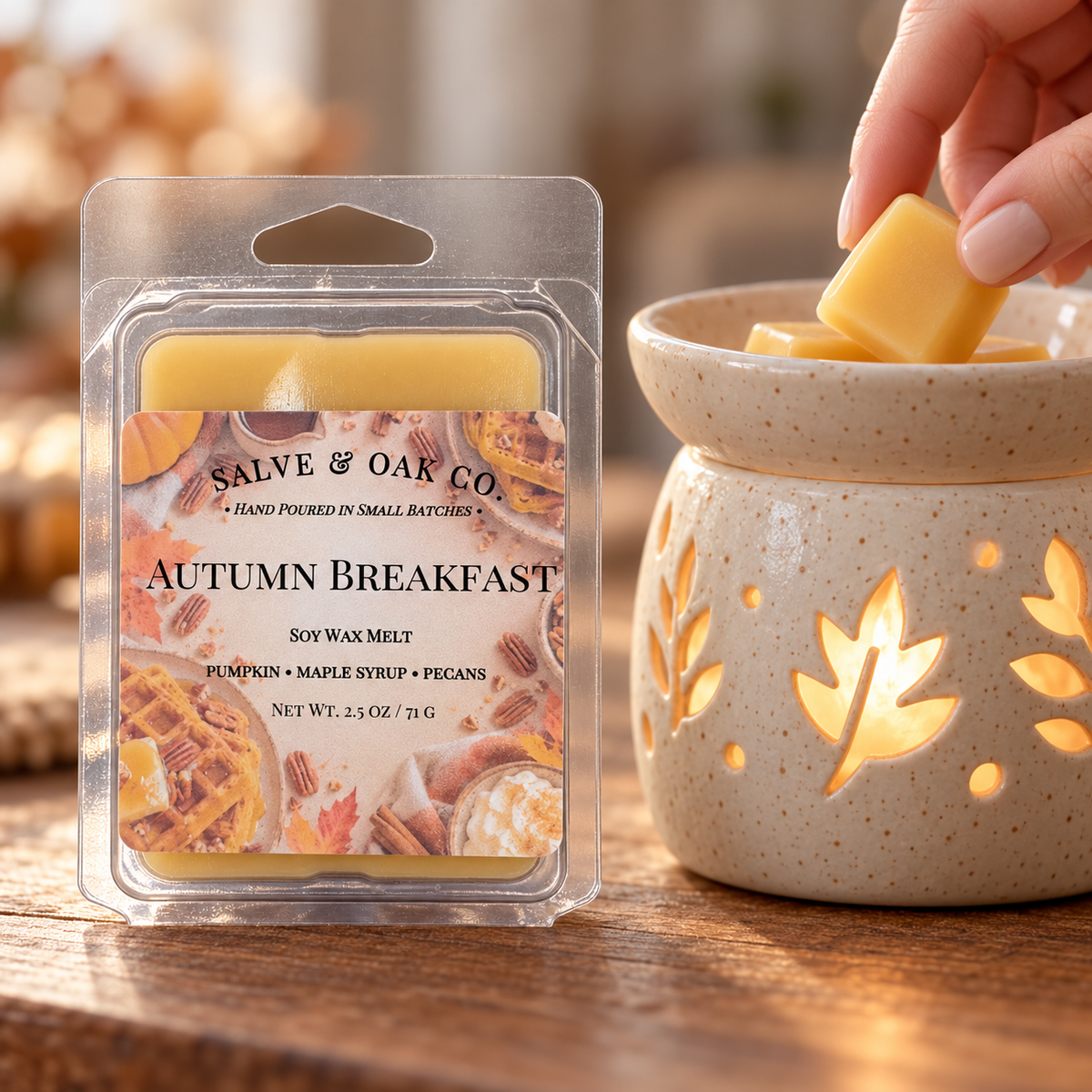 Hand placing a golden yellow Autumn Breakfast wax cube into a glowing ceramic warmer beside its package.