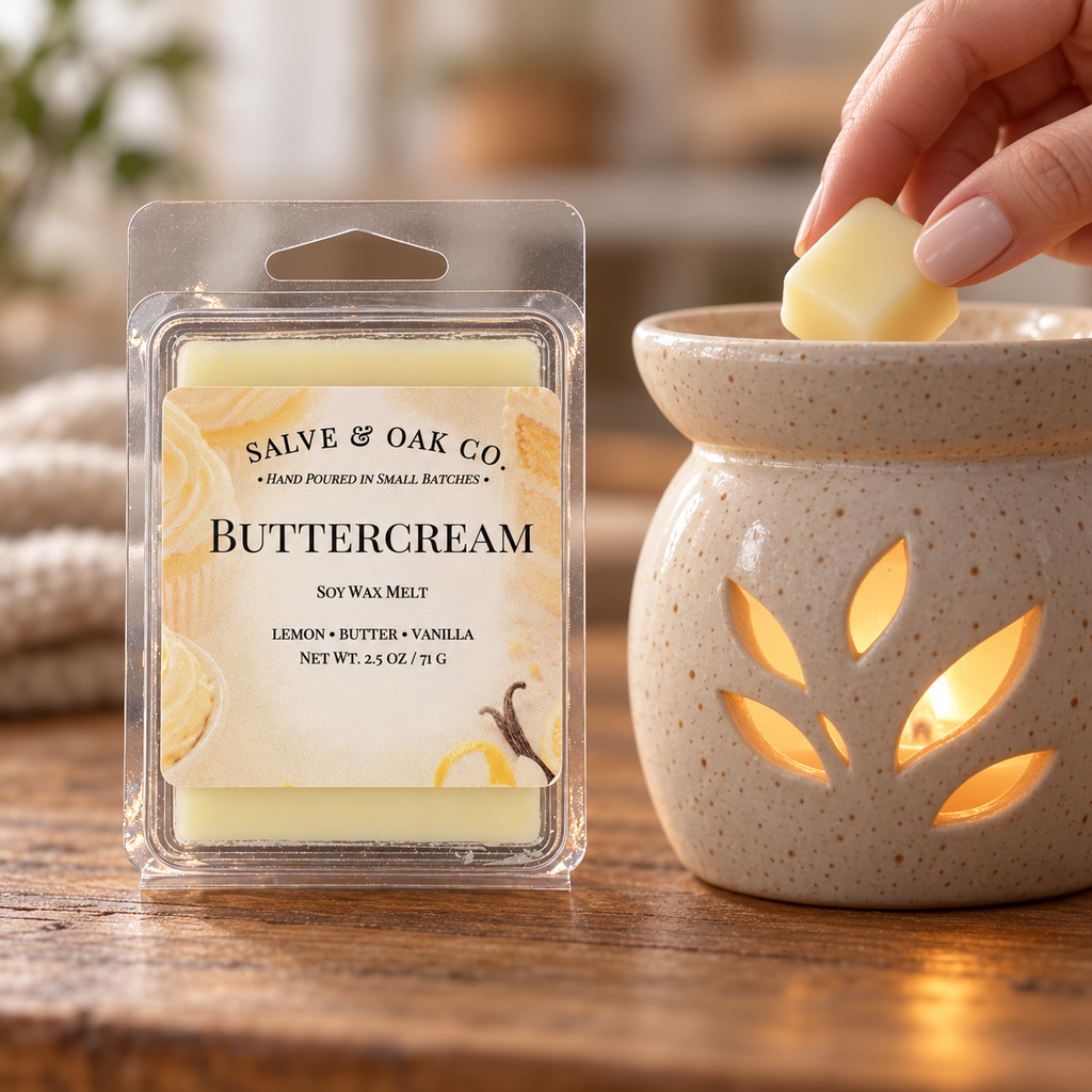 Hand placing a pale yellow Buttercream wax cube into a glowing ceramic warmer beside its package.