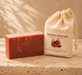 Crimson Orchard grass-fed tallow and goat milk bar soap beside its muslin packaging on a warm neutral background