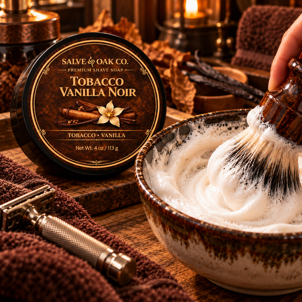 Tobacco Vanilla Noir shave soap beside a lathered shave bowl, shaving brush, razor, and warm brown grooming setup