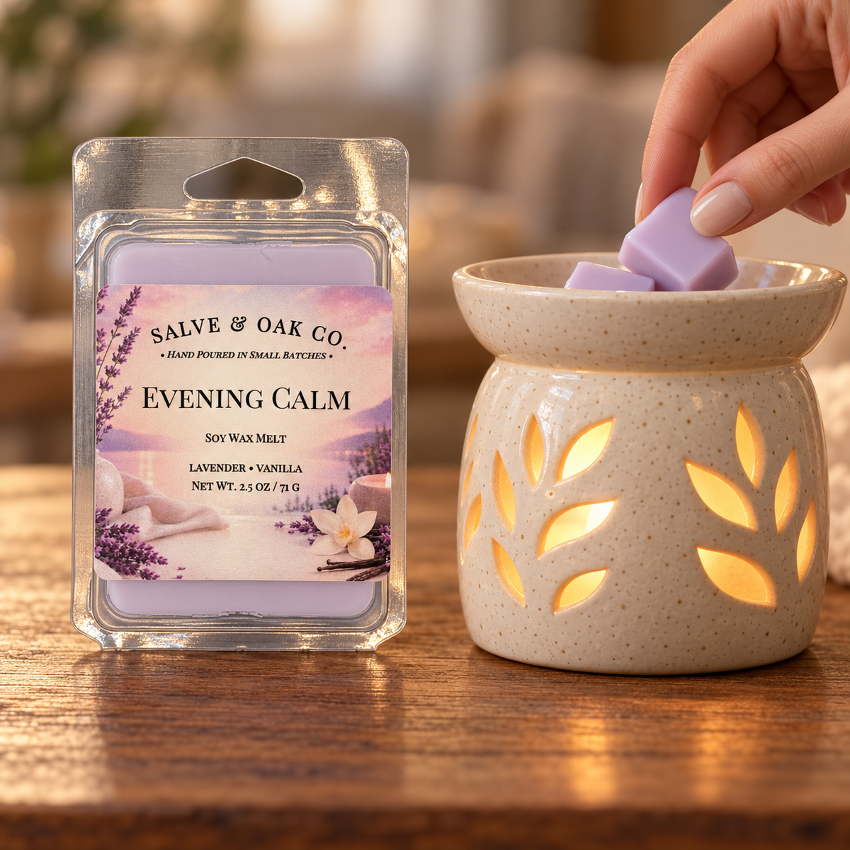 Hand placing a lavender Evening Calm wax cube into a glowing ceramic warmer beside its package.